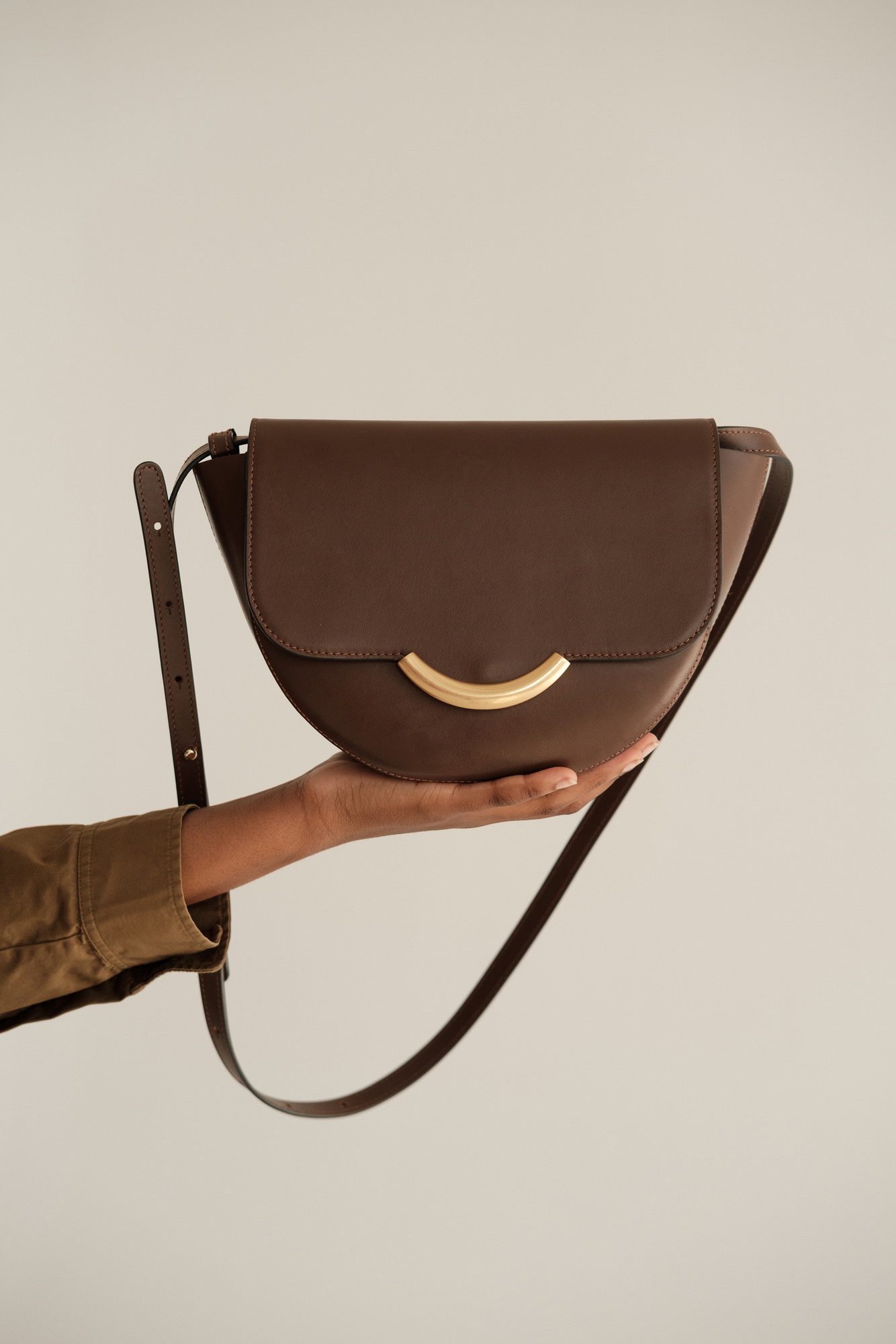 a person holding a brown leather cross body bag
